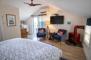 a bedroom with a bed and two chairs and a television at The Trellis House in Ogunquit