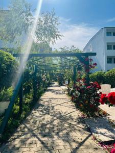 a garden path with flowers and a blue arbor at Hotel Angely in Eforie Nord