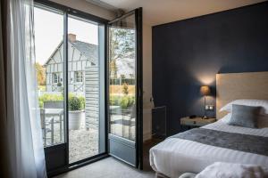 a bedroom with a bed and a sliding glass door at Hotel de l'Abbaye; BW Premier Collection in Le Tronchet
