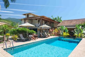 a villa with a swimming pool in front of a house at Odoyá Casa Hotel in Paraty