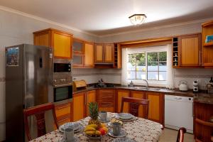 a kitchen with wooden cabinets and a table with fruit on it at Paradise House Calheta in Calheta