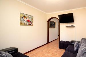 a living room with a couch and a flat screen tv at Paradise House Calheta in Calheta
