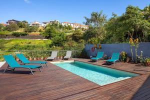 a deck with chairs and a swimming pool at Paradise House Calheta in Calheta