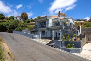 a white house on a hill next to a street at Paradise House Calheta in Calheta