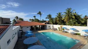 a swimming pool with umbrellas next to a house at Pousada Holy Salt Cumbuco in Caucaia