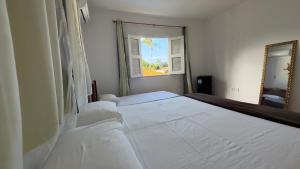 a bedroom with a large white bed with a mirror at Pousada Holy Salt Cumbuco in Caucaia