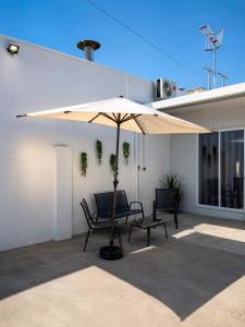 a patio with an umbrella and two chairs under it at El Rinconcito de la Jara con Parking para varios coches in Sanlúcar de Barrameda