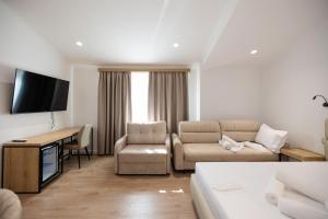 a living room with a couch and a desk and a television at Hotel Petro in Vlorë
