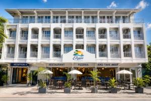 a large white building with tables and umbrellas at Elysee Vacances in Trou aux Biches