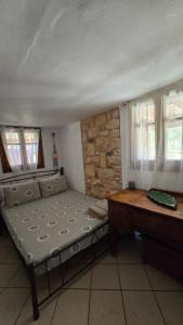 a bedroom with a bed and a desk and windows at Lekania House in Káto Nisí
