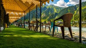 a row of tables and chairs next to a river at GUREZ LUXURY Resort by GRITTI CASTLE in Wāmpor
