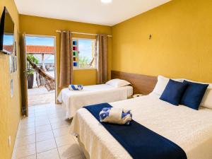a hotel room with two beds and a balcony at Pousada Estrela da Luz Refúgio in Muriú