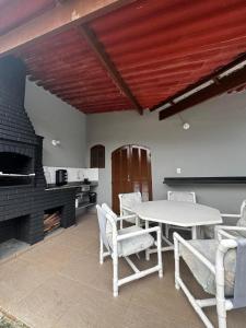 a kitchen with a table and chairs and a fireplace at Casa de Praia com Piscina e Espaço Gourmet in Bertioga