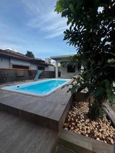 a swimming pool with a wooden deck next to a house at Casa de Praia com Piscina e Espaço Gourmet in Bertioga