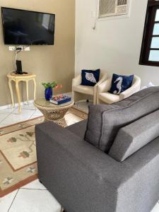 a living room with a couch and a tv at Casa de Praia com Piscina e Espaço Gourmet in Bertioga