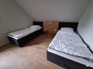 two beds in a small room with wooden floors at Ferienwohnung Alte Schule in Lonnerbecke