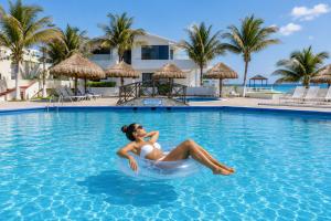 a woman is sitting in a swimming pool at Beachfront Three-Story Coastal Penthouse, 3BR-3BA in Cancún