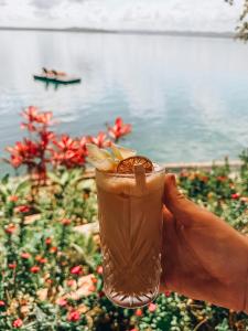 a person holding a drink in their hand next to the water at Bolontiku Boutique Hotel Member of the Cayuga Collection in Flores +73 photos