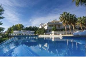 a large swimming pool with a house and palm trees at Giardino del carrubo in Marina di Ragusa