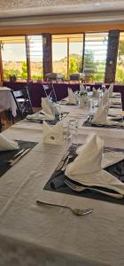 a dining room with tables with white napkins and silverware at Juniper Park Resort in Nyahururu