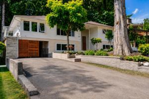 a driveway in front of a house with a tree at Cozy Coastal Retreat Close to Beach Park in Port Moody