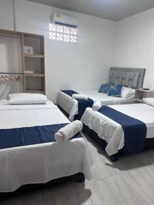 a room with three beds in a room at Hotel San Luis in Buga