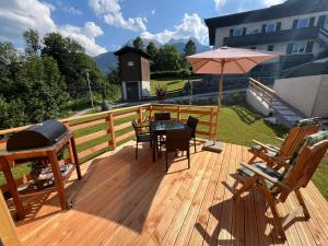 a wooden deck with a grill and a table and chairs at Saalach Chalet in Lofer
