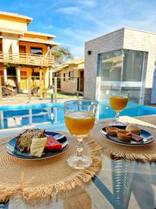 two glasses of wine and food on a table by a pool at Pousada Cipó Cana in Santana do Riacho