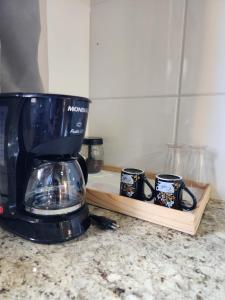 a coffee maker and three coffee cups on a counter at Pousada Cipó Cana in Santana do Riacho