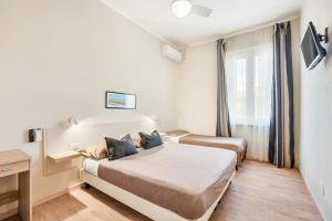 a hotel room with two beds and a window at Hotel La Perla in Marina di Massa