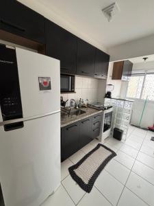 a kitchen with black cabinets and a white refrigerator at Lazer Oceanos in São Vicente