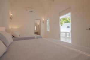a white bedroom with two beds and a window at Cabrero House Boutique in Cartagena de Indias