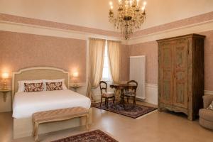 a bedroom with a bed and a table and a chandelier at Castello di Morozzo Guest House in Morozzo +14 photos