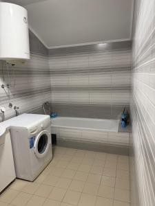 a bathroom with a washing machine and a bath tub at Apartman M&S in Golubovci