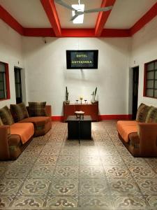 a living room with couches and a tv on the wall at Hotel Antequera in Oaxaca City