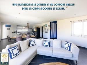 a living room with a white couch with blue and white pillows at Les Alizés in Plouhinec
