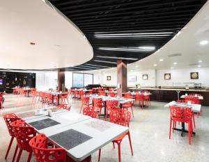 a dining room with red chairs and tables at Hotel EJM PREMIUM in Irapuato
