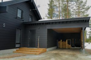 a black house with a door and stairs on it at Villa Liemu, Winter season included 2 lift tickets in Äkäslompolo