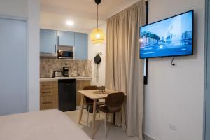 a kitchen with a table and a tv on a wall at Colonial studio with 2 Beds - Patio Español in Santo Domingo