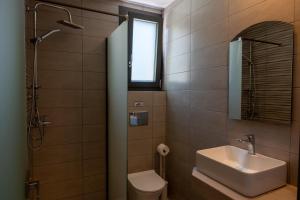 a bathroom with a sink and a toilet and a mirror at Psarras Deluxe Suites in Limenas +19 photos