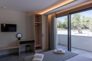 a bedroom with a large window and a desk with towels at Psarras Deluxe Suites in Limenas