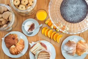 a table topped with plates of pastries and orange juice at Hotel La Perla in Marina di Massa