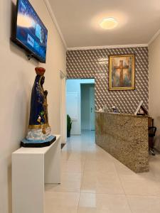 a living room with a television and a counter at Hotel Pousada Romanos in Aparecida