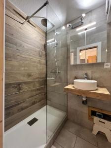 a bathroom with a glass shower and a sink at Chaleureux appartement moderne in Briançon