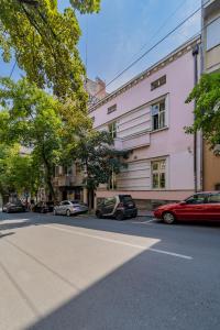 a pink building with cars parked on the side of a street at City Code InJoy RENEW in Belgrade