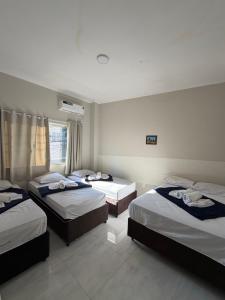 a hotel room with three beds in it at Hotel Pousada Romanos in Aparecida