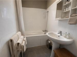 a white bathroom with a sink and a bath tub at La maison boîte à gâteaux in Lapalme