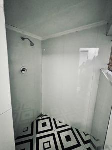a bathroom with a shower with a black and white floor at Ntinti Stays Cottage in Ndola +5 photos