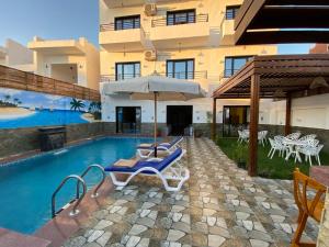 a pool with chairs and an umbrella next to a building at pure peace hotel in Luxor