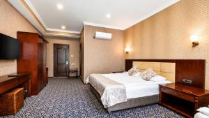 a hotel room with a bed and a flat screen tv at Ruma Qala Hotel in Sheki +103 photos